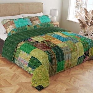May include: A green and blue patchwork quilt with a kantha stitch design. The quilt is made of recycled saris and is perfect for adding a touch of bohemian style to any bedroom.