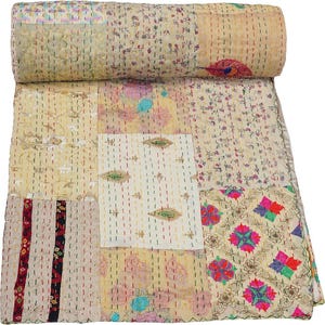 Peut inclure: Une courtepointe patchwork avec une variété de motifs floraux et géométriques dans des tons crème, rose, bleu et vert. La courtepointe est en coton et est cousue à la main.