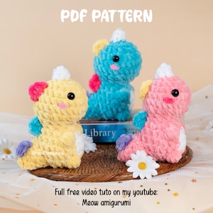 Może przedstawiać: Trzy pluszowe zabawki amigurumi w kształcie jednorożca, wykonane na szydełku w kolorze żółtym, niebieskim i różowym. Zabawki siedzą na wiklinowym koszu z białą stokrotką przed nimi. Tekst "PDF PATTERN" znajduje się w górnej części obrazu. Tekst "Full free video tuto on my youtube: Meow amigurumi" znajduje się w dolnej części obrazu.