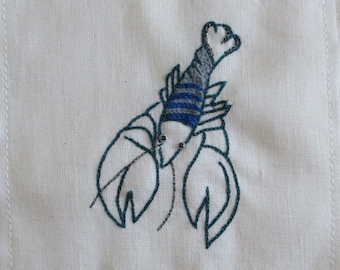 Broderie à la main. Broderie décorative. Le petit homard bleu du mois de mai. Fabrication artisanale. Art textile.