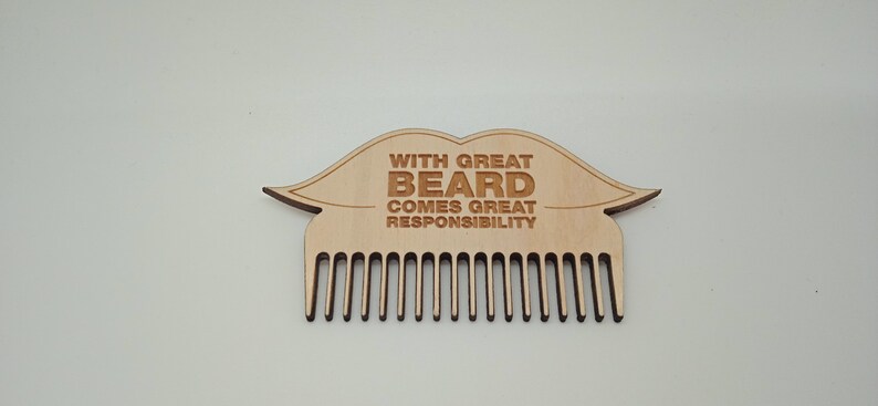 Op de afbeelding: Een houten baardkam met een  moustachevormig handvat. Het handvat is gegraveerd met de tekst "With great beard comes great responsibility".