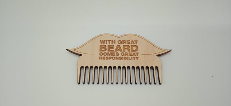 Op de afbeelding: Houten baardkam in de vorm van een snor met de tekst "With great beard comes great responsibility".