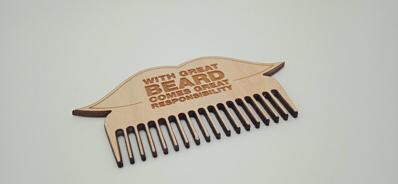 Op de afbeelding: Houten baardkam met een lipvormig ontwerp en de tekst "With great beard comes great responsibility".