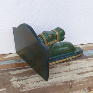 May include: A dark green wooden bookend featuring a sculpted horse head and neck extending from a vertical support panel. The horse figure is adorned with gold-coloured trim along the bridle and the base, showcasing a distressed finish throughout.