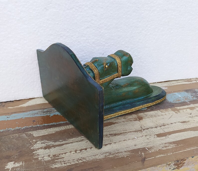 May include: A dark green wooden bookend featuring a sculpted horse head and neck extending from a vertical support panel. The horse figure is adorned with gold-coloured trim along the bridle and the base, showcasing a distressed finish throughout.