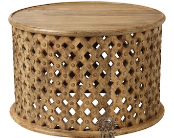 May include: A round wooden coffee table featuring a natural brown finish and a cylindrical base with a repeating lattice pattern of diamond-shaped cutouts and circular accents. The text ANAND ART AND CRAFT GIFT ARTICLES DECORATIVE ITEMS is visible.