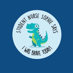 Op de afbeelding: Een blauwe cirkel met een groene dinosaurus erin. De tekst rond de dinosaurus zegt "Student Nurse Sophie Says I Was Brave Today!"