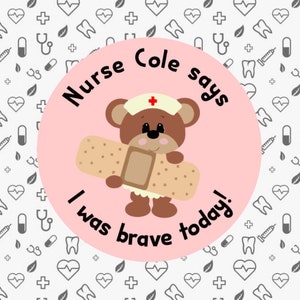 Op de afbeelding: Een roze cirkel met een bruine teddybeer die een witte verpleegstersmuts met een rood kruis draagt. De teddybeer houdt een bruin verband vast. De tekst rond de teddybeer zegt "Nurse Cole says I was brave today!"