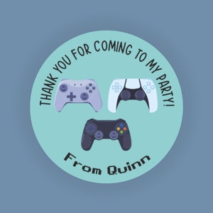 May include: A light blue circle sticker with the text "Thank you for coming to my party!" and "From Quinn" in a pixelated font. Three video game controllers are shown in the center of the sticker: a purple and white controller, a white controller, and a black controller.