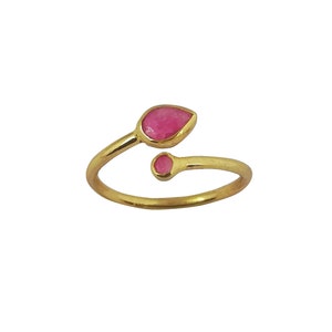 May include: A gold ring with two pink gemstone accents. The larger gemstone is a teardrop shape and the smaller gemstone is round.