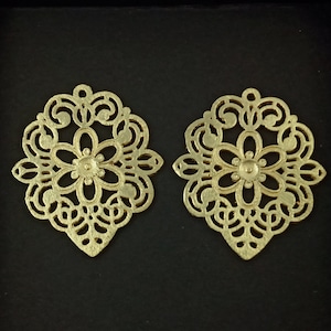 May include: Two gold-colored metal filigree earrings with a floral design.