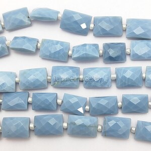 May include: Close-up of a strand of light blue faceted rectangular beads. The beads are strung together with small silver-colored connectors. The beads have a geometric, crystalline appearance, and are a soft, pastel blue color.