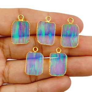 Könnte beinhalten: Fünf rechteckige Anhänger aus irisierendem Opal mit vergoldeten Kanten. Jeder Anhänger hat oben eine Öse zum Anbringen an einer Kette oder Schnur.