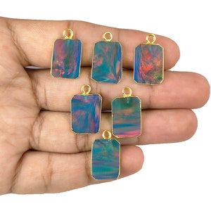 May include: Six iridescent opal rectangle pendants with gold-plated edges. The pendants are approximately 2.5 cm long and 1.25 cm wide.