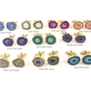 May include: A collection of solar quartz cufflinks with gold-toned metal hardware. The set includes pairs in blue, grey, pink, peach, violet, green, purple, yellow, white, and aqua, each labeled with its respective color name below the pair.