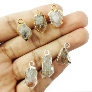 Pode incluir: Seis pingentes de cristal de quartzo bruto com argolas de salto de ouro e prata. Os cristais s&atilde;o transparentes e t&ecirc;m uma textura natural e &aacute;spera.