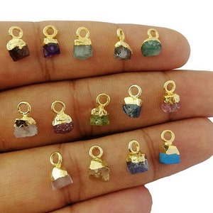 Puede incluir: Surtido de 12 colgantes de piedras preciosas chapados en oro. Cada colgante presenta una piedra preciosa de color diferente, incluyendo azul, verde, rosa, rojo y morado. Los colgantes son perfectos para la elaboración de joyas o para agregar un toque de brillo a cualquier proyecto.