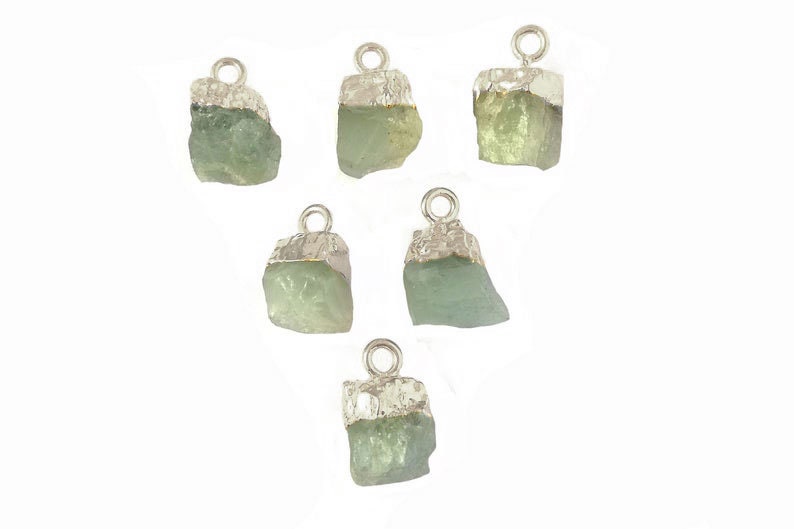 May include: Six silver and green gemstone pendants. Each pendant features a raw, irregular shaped green gemstone with a silver bail.
