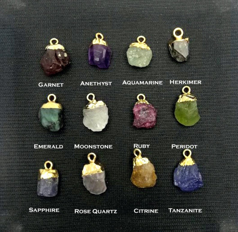 May include: Assortment of 12 gemstone pendants with gold settings. Each pendant features a different gemstone, including garnet, amethyst, aquamarine, herkimer, emerald, moonstone, ruby, peridot, sapphire, rose quartz, citrine, and tanzanite.