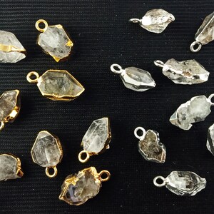 Pode incluir: Uma cole&ccedil;&atilde;o de 15 pingentes de cristal de quartzo transparente com detalhes dourados e prateados. Os pingentes s&atilde;o de diferentes formas e tamanhos, e alguns t&ecirc;m uma cor quartzo fumado.