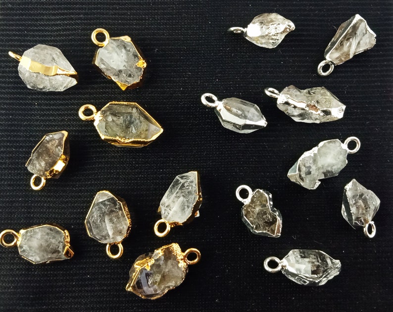 Pode incluir: Uma cole&ccedil;&atilde;o de 15 pingentes de cristal de quartzo transparente com detalhes dourados e prateados. Os pingentes s&atilde;o de diferentes formas e tamanhos, e alguns t&ecirc;m uma cor quartzo fumado.