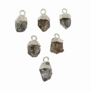 May include: Six silver charms with raw, clear quartz crystals. Each charm has a loop for attaching to a necklace or bracelet.