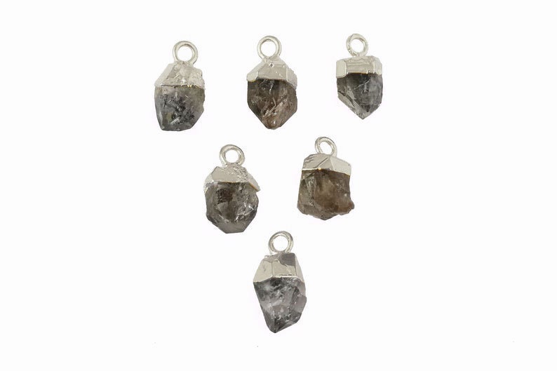 May include: Six silver charms with raw, clear quartz crystals. Each charm has a loop for attaching to a necklace or bracelet.