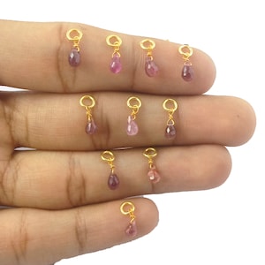 Pode incluir: Dez pingentes banhados a ouro com gotas de pedras preciosas cor-de-rosa. Cada pingente tem um pequeno laço para prender em joias.