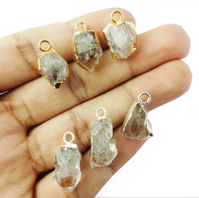 Pode incluir: Seis pingentes de cristal de quartzo bruto com argolas de salto de ouro e prata. Os cristais s&atilde;o transparentes e t&ecirc;m uma textura natural e &aacute;spera.