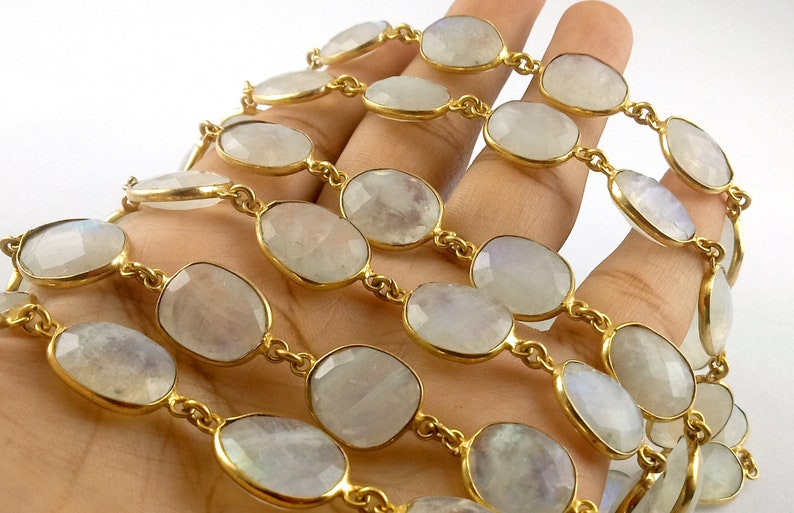 Peut inclure: Un brin de perles de pierre de lune de forme ovale avec une cha&icirc;ne dor&eacute;e. Les perles sont de couleur blanc laiteux avec un l&eacute;ger reflet iris&eacute;.