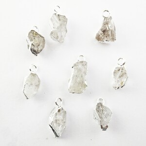 Pode incluir: Oito pingentes de prata com cristais de quartzo transparentes. Cada pingente tem um la&ccedil;o para prender a uma corrente ou cord&atilde;o.