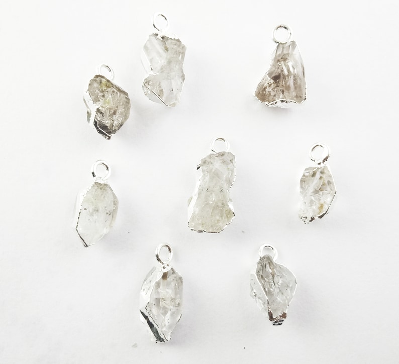 Pode incluir: Oito pingentes de prata com cristais de quartzo transparentes. Cada pingente tem um la&ccedil;o para prender a uma corrente ou cord&atilde;o.
