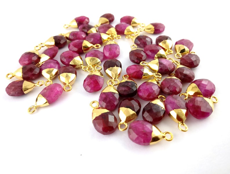 Op de afbeelding: Een groep roze edelsteen druppel hangers met vergulde springringen. De hangers zijn gefacetteerd en hebben een glanzende afwerking.