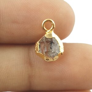 Pode incluir: Pingente folheado a ouro com um cristal de quartzo transparente com design facetado. O pingente tem um la&ccedil;o na parte superior para prender a uma corrente ou cord&atilde;o.