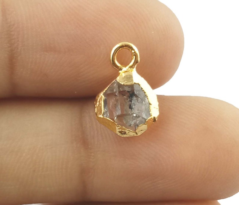 Pode incluir: Pingente folheado a ouro com um cristal de quartzo transparente com design facetado. O pingente tem um la&ccedil;o na parte superior para prender a uma corrente ou cord&atilde;o.