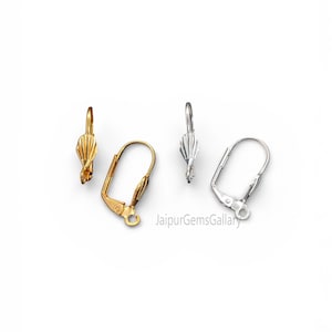 Peut inclure: Quatre apprêts de boucles d'oreilles en or et argent sont présentés sur fond blanc. Les apprêts comprennent des fermoirs à levier et des dessus décoratifs. Les apprêts dorés ont une finition chaude et brillante, tandis que les argentés ont un aspect métallique brillant.