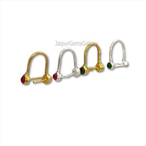 Puede incluir: Cuatro piercings de nariz en tonos dorados y plateados, cada uno con una pequeña gema. Las gemas son rojas y verdes. El texto "JaipurGemsGallery" es visible.