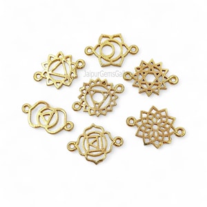 Könnte beinhalten: Goldfarbene Metall-Chakra-Verbinder in verschiedenen geometrischen Designs. Jeder Verbinder hat eine einzigartige Form mit kreisförmigen Schlaufen an jedem Ende zur Befestigung. Die Verbinder werden auf einer weißen Oberfläche dargestellt.