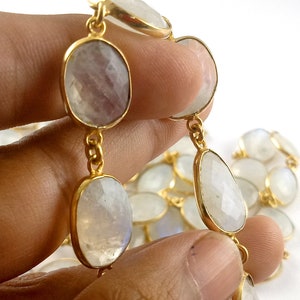 Peut inclure: Un collier en cha&icirc;ne dor&eacute;e avec des perles de pierre de lune de forme ovale. Les perles sont de couleur blanc laiteux avec un l&eacute;ger reflet iris&eacute;.