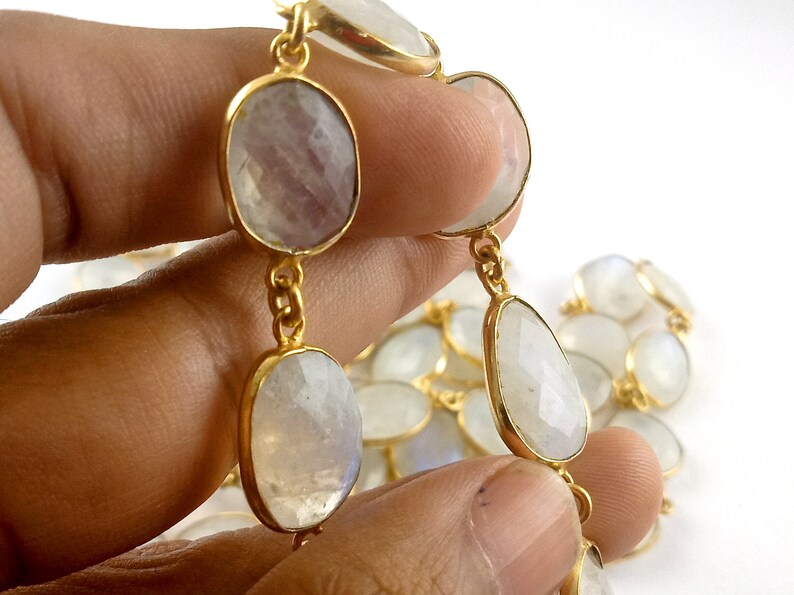Peut inclure: Un collier en cha&icirc;ne dor&eacute;e avec des perles de pierre de lune de forme ovale. Les perles sont de couleur blanc laiteux avec un l&eacute;ger reflet iris&eacute;.