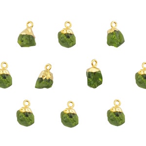 May include: Ten gold-plated pendants with green gemstone accents. Each pendant features a unique, irregular shape and a small loop for attaching to jewelry.