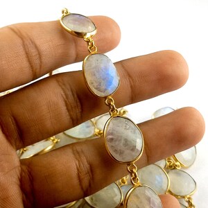 Peut inclure: Un collier en cha&icirc;ne dor&eacute;e avec des perles de pierre de lune de forme ovale. Les perles sont de couleur blanc laiteux avec des reflets iris&eacute;s bleus et verts.