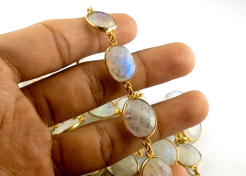 Peut inclure: Un collier en cha&icirc;ne dor&eacute;e avec des perles de pierre de lune de forme ovale. Les perles sont de couleur blanc laiteux avec des reflets iris&eacute;s bleus et verts.