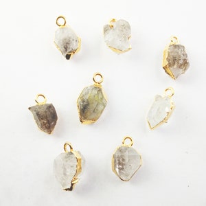 Pode incluir: Oito pingentes de cristal banhados a ouro com um visual cru e natural. Cada pingente tem um la&ccedil;o para prender a uma corrente ou cord&atilde;o.