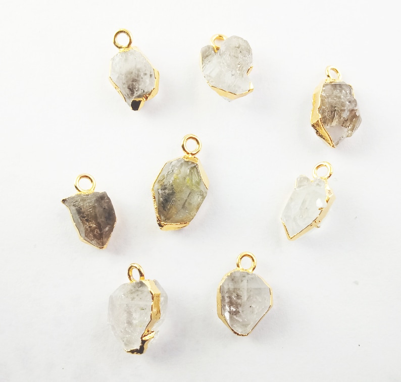Pode incluir: Oito pingentes de cristal banhados a ouro com um visual cru e natural. Cada pingente tem um la&ccedil;o para prender a uma corrente ou cord&atilde;o.