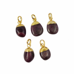 May include: Five gold-plated pendants with a dark purple gemstone. Each pendant is shaped like a teardrop and has a gold bail.