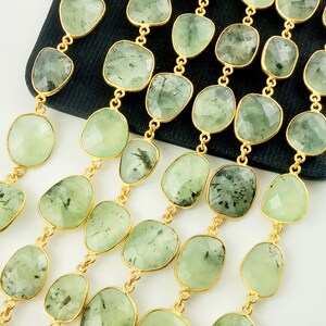 May include: A strand of green gemstone beads with gold accents. The beads are faceted and have a slightly irregular shape. The beads are strung on a gold chain.