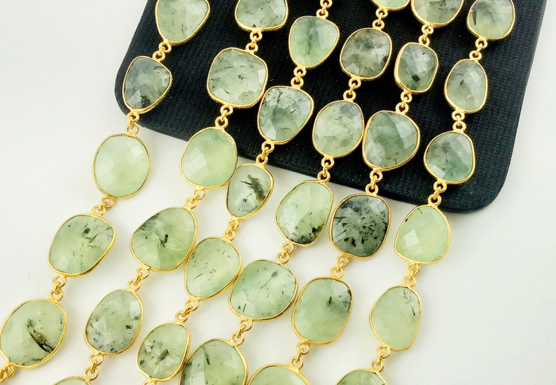 May include: A strand of green gemstone beads with gold accents. The beads are faceted and have a slightly irregular shape. The beads are strung on a gold chain.