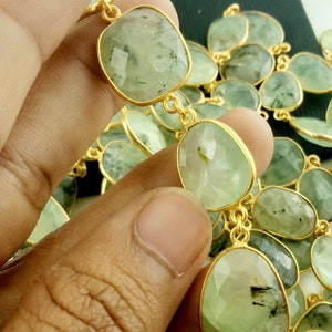May include: A strand of green gemstone beads with gold accents. The beads are faceted and have a slightly irregular shape. The beads are strung on a gold chain.