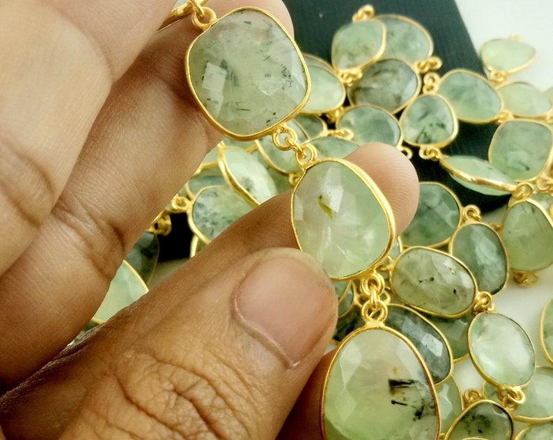 May include: A strand of green gemstone beads with gold accents. The beads are faceted and have a slightly irregular shape. The beads are strung on a gold chain.
